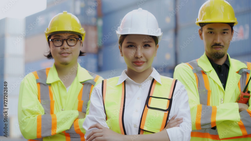 A team of engineers in safety uniforms stand with their arms crossed and smile at the camera at a container yard. leadership successful employees teamwork concept A team of engineers in safety uniforms stand with their arms crossed and smile at the camera at a container yard. leadership successful employees teamwork concept