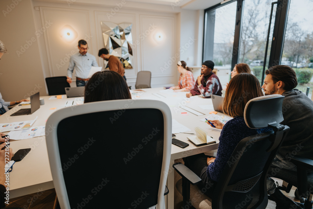 Creative team working on project with discussions in a modern meeting room. Focus on teamwork, communication, and corporate environment.