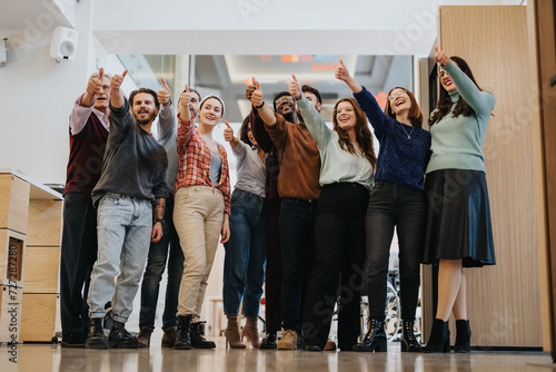 Obraz na plátne A group of smiling people standing indoors, joyfully raising their hands up in the air to celebrate success and unity