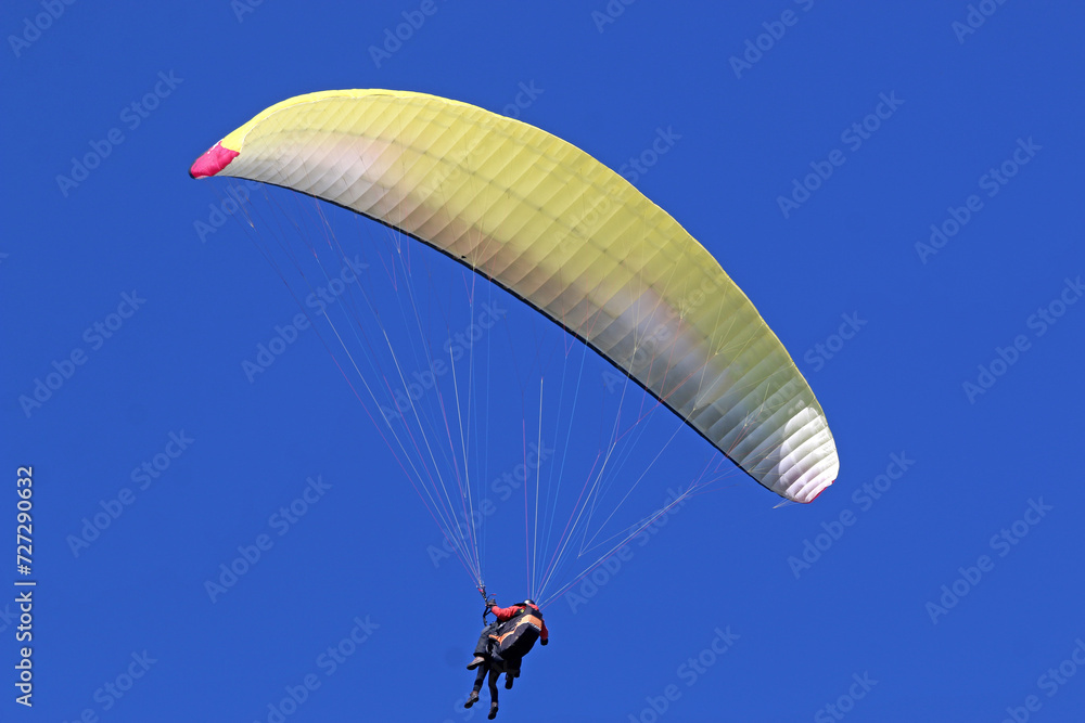 Tandem Paraglider flying in a blue sky Tandem Paraglider flying in a blue sky