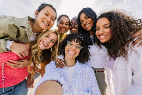 Diverse group of happy young female friends having fun taking selfie portrait together outdoors. Female friendship and youth concept. photo