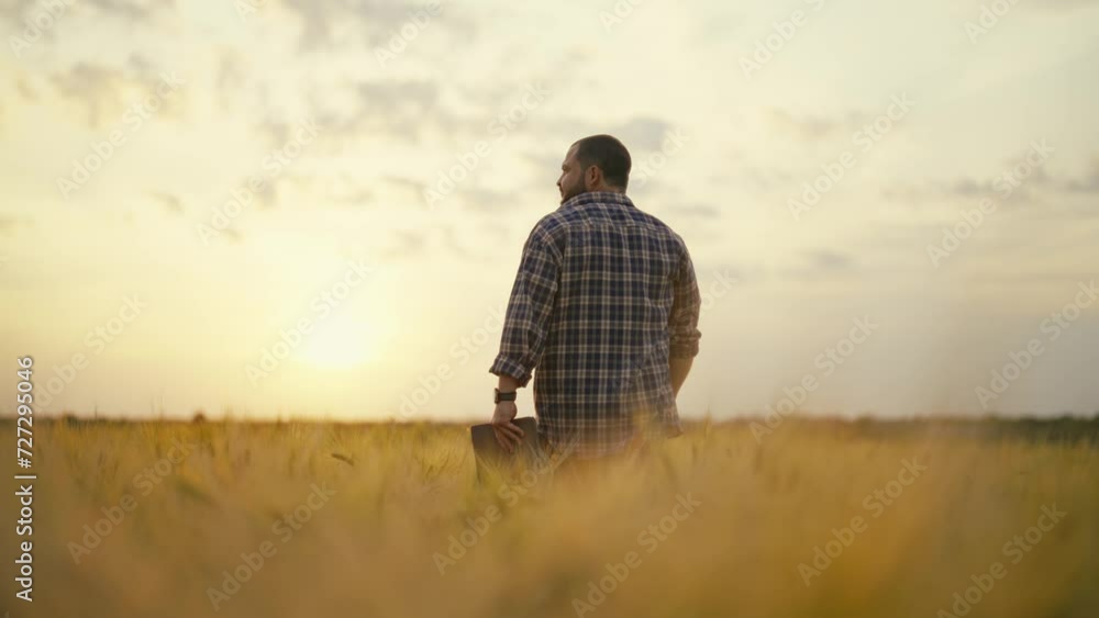 Man botanist with tablet works in field. Farmer agronomist checks ripe wheat, growth, collects data. Scientist engineer conducts research of plant cultivation. Agribusiness, country work concept. Man botanist with tablet works in field. Farmer agronomist checks ripe wheat, growth, collects data. Scientist engineer conducts research of plant cultivation. Agribusiness, country work concept.