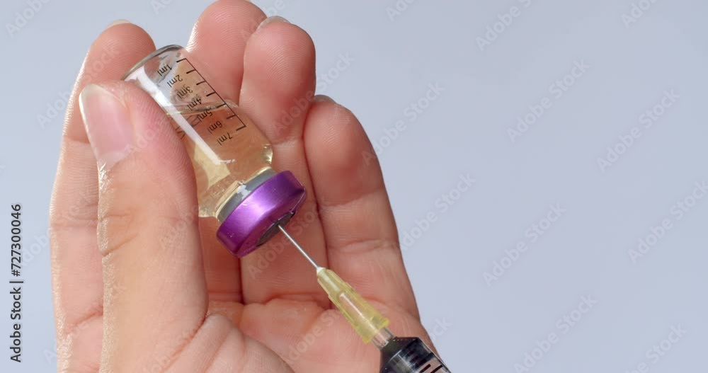 Using syringe suck out of purple bottle by turning the medicine bottle ...