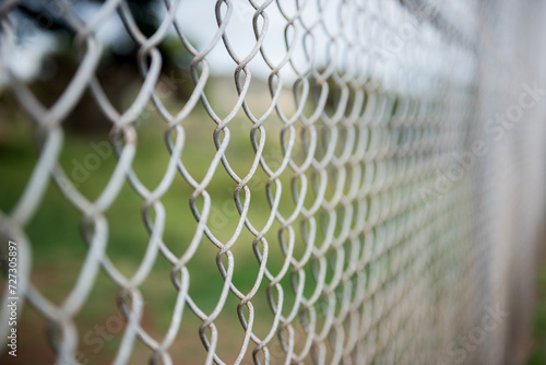 Fence with metal grid in perspective. Metal chain-link fence as the background, street photo, close-up,