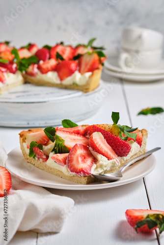 Slice of strawberry tart with butter cream on a white wooden table. French delicious dessert. Fresh and beautiful tart.
