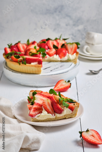 Slice of strawberry tart with butter cream on a white wooden table. French delicious dessert. Fresh and beautiful tart.