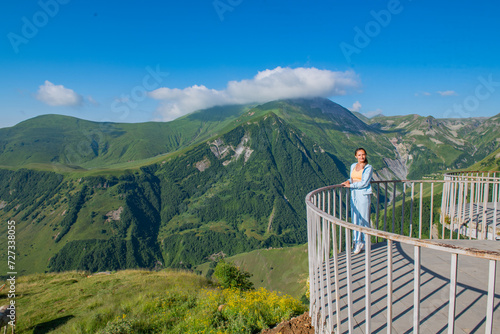 Young Woman in Blue Outfit Standing on Observation Deck with Mountain View