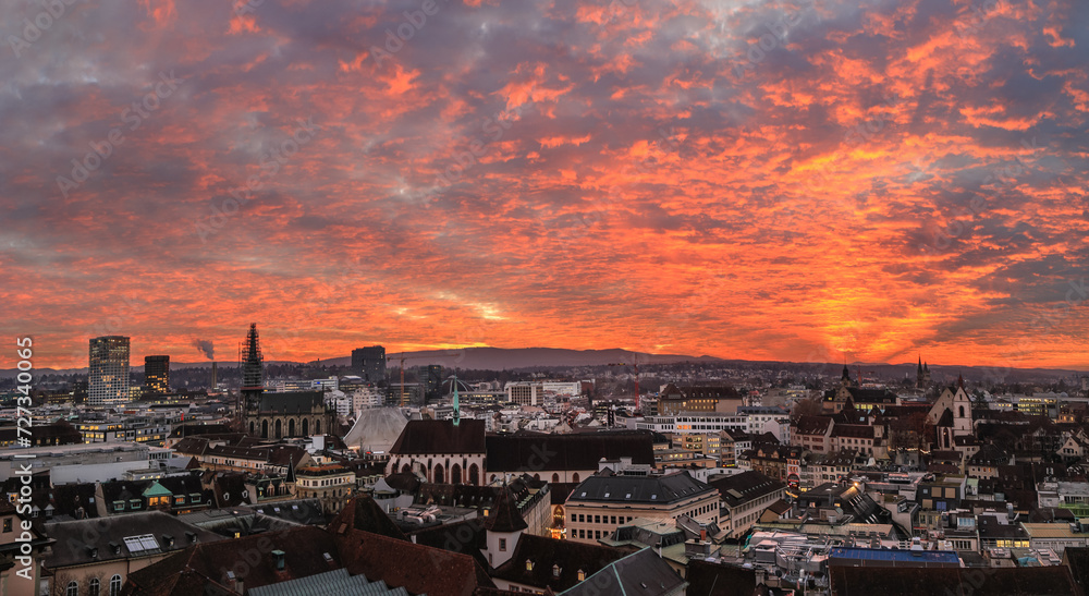 Burning sunset over the Swiss old city Basel in the dusk viewed high above on the Munster Church tower.