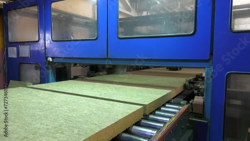 Large round industrial knives cuts a layer of mineral wool on the conveyor of a mineral wool plant.  Unloading conveyor with raw materials for the production of thermal insulation from mineral wool.
