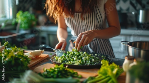 Woman in the kitchen preparing celery and green onion salad.