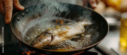 Fish being cooked in a hot pan with oil.