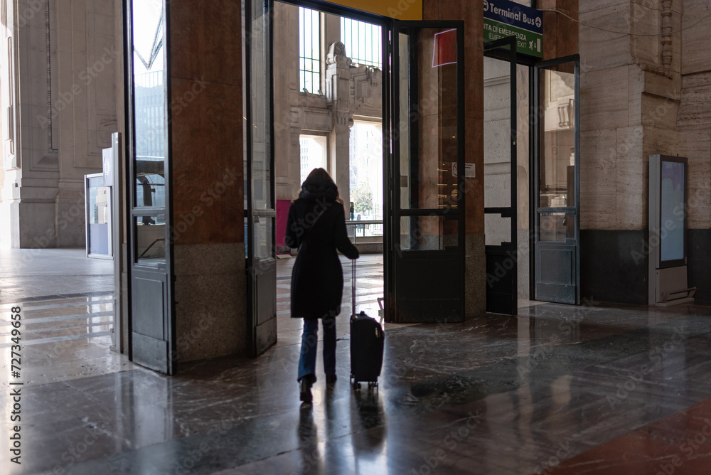 Tourist leaves Milan Central Station with his suitcase Tourist leaves Milan Central Station with his suitcase
