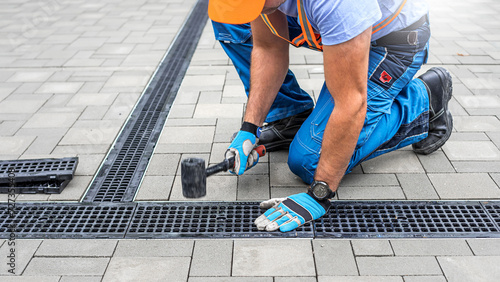 Laying interlocking paving. A worker is placing the grutter grid to drainage channel. photo