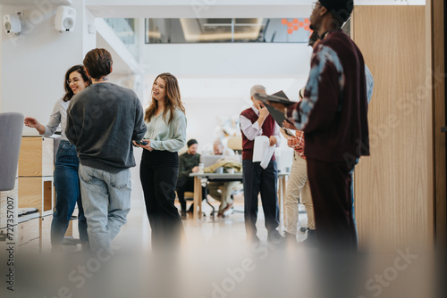A group of casually dressed business colleagues engaging in a friendly conversation in a bright, contemporary office space. photo