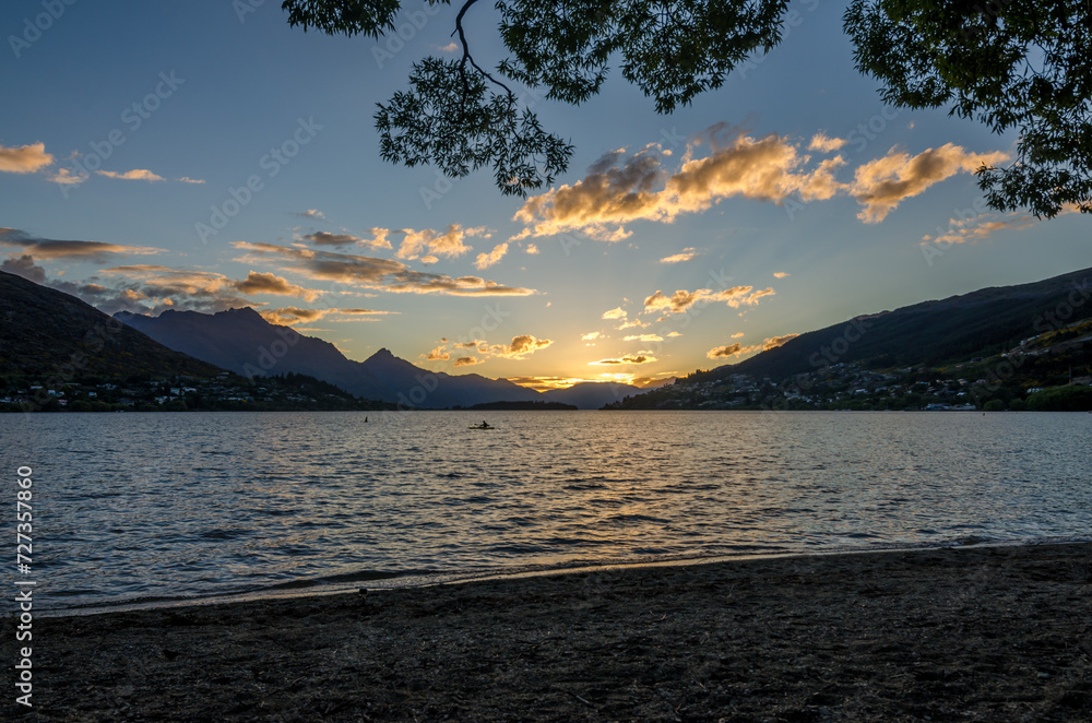Sunset in Queenstown with Canone visible floating a lake in a foreground.