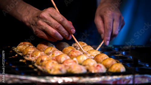A Japanese vendor prepare a Takoyaki on hot pan food Japan. Fried octopus balls
