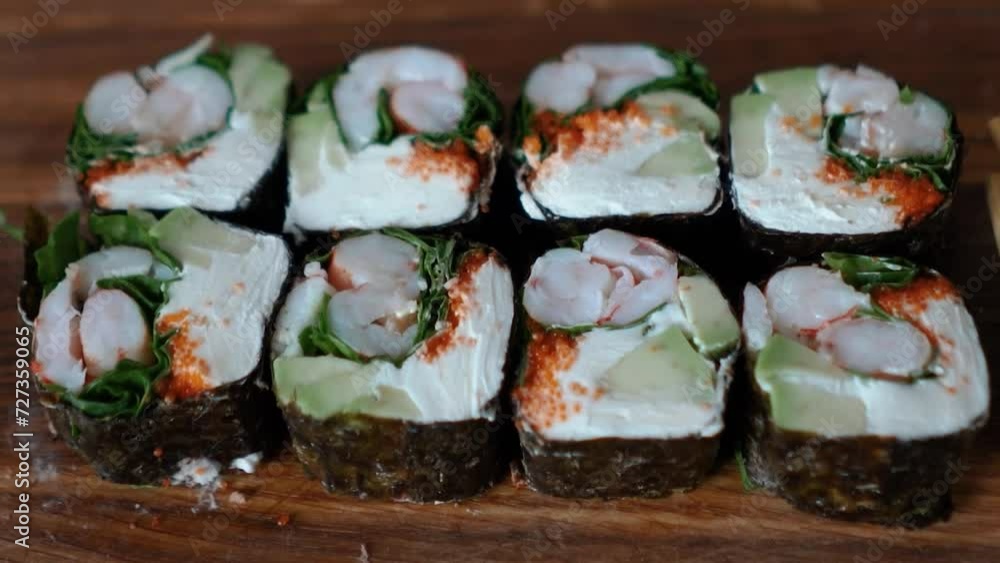 Japanese food with rice, red raw fish, cream cheese, salmon, shrimp, avocado and nori. Appetizing sushi set with rolls on the table. Incredibly tasty and expensive food from a sushi chef Japanese food with rice, red raw fish, cream cheese, salmon, shrimp, avocado and nori. Appetizing sushi set with rolls on the table. Incredibly tasty and expensive food from a sushi chef