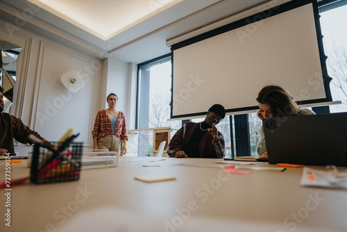Focused team members in a business meeting, exchanging ideas in a well-lit contemporary workspace. A concept of teamwork, diversity, and collaboration.