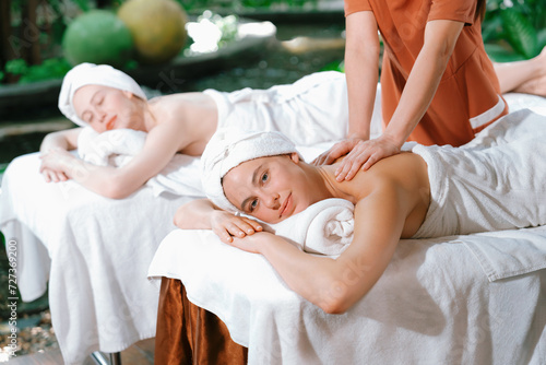 A portrait of two young attractive woman lie on bed during having back massage by a professional masseur at outdoor surrounded by peaceful natural environment. Healthy and beauty concept. Tranquility.