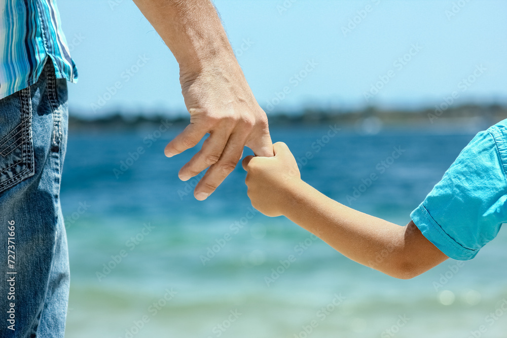 A happy dad holds the hand of a child by the greek sea in nature A happy dad holds the hand of a child by the greek sea in nature