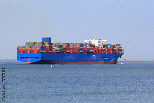 a big container ship navigates in the westerschelde sea towards the port of antwerp closeup