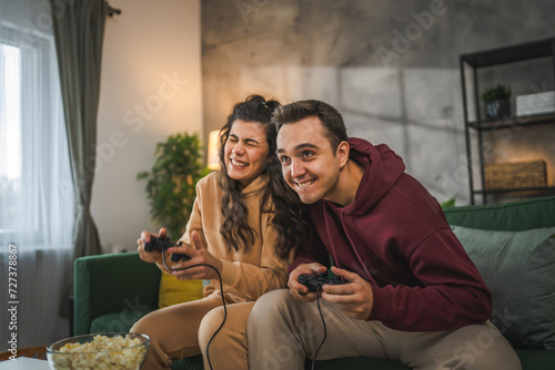 couple man and woman husband wife play console video games at home photo