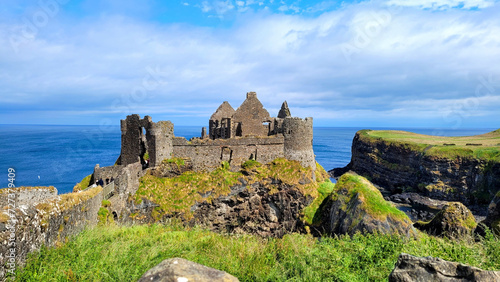 Ruins of the medieval Dunluce Castle along the green cliffs of the Causeway Coast, Northern Ireland