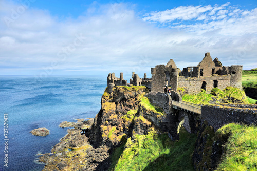 Ruins of the medieval Dunluce Castle on green cliffs overlooking the North Atlantic ocean. Causeway Coast, Northern Ireland.