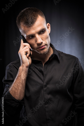 Young man in blacxk shirt talking on a mobile phone photo