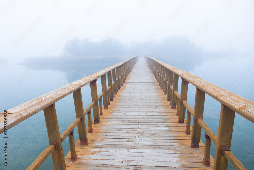 Fototapeta premium Misty lake walkway disappearing into the horizon