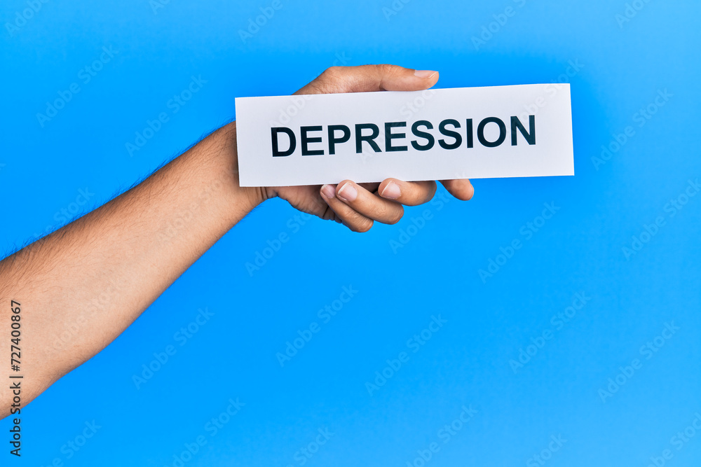 Hand of caucasian man holding paper with depression word over isolated blue background Hand of caucasian man holding paper with depression word over isolated blue background