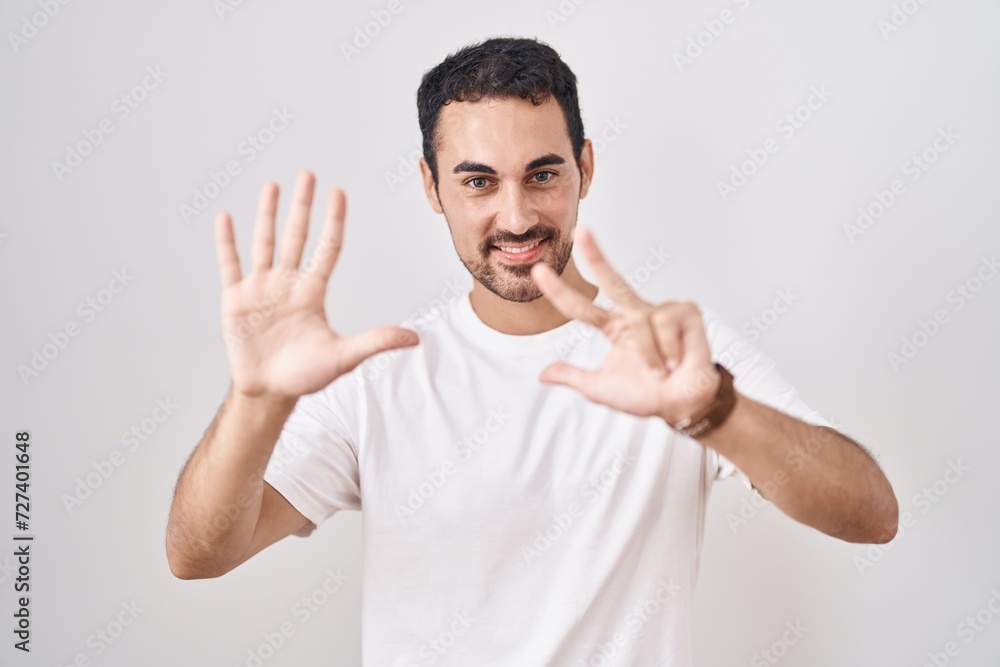 Handsome hispanic man standing over white background showing and pointing up with fingers number eight while smiling confident and happy. Handsome hispanic man standing over white background showing and pointing up with fingers number eight while smiling confident and happy.