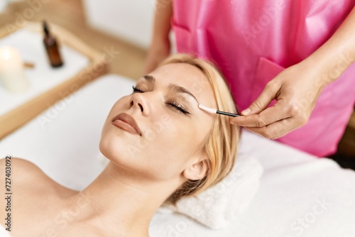 Young caucasian woman lying on table having eyelashes treatment at beauty salon