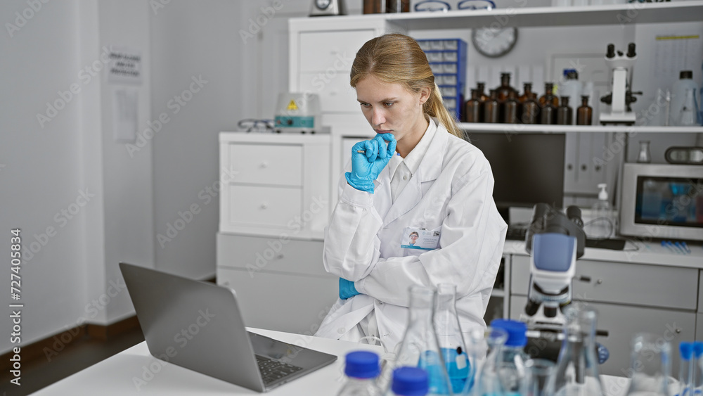Thoughtful woman scientist analyzing data on laptop in laboratory Thoughtful woman scientist analyzing data on laptop in laboratory