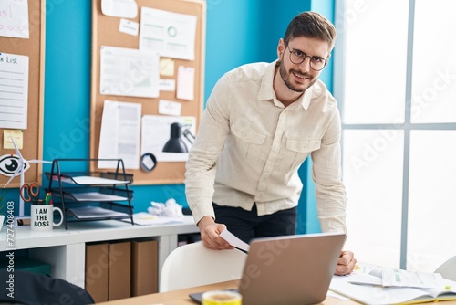 Young caucasian man business worker using laptop writing on document at office
