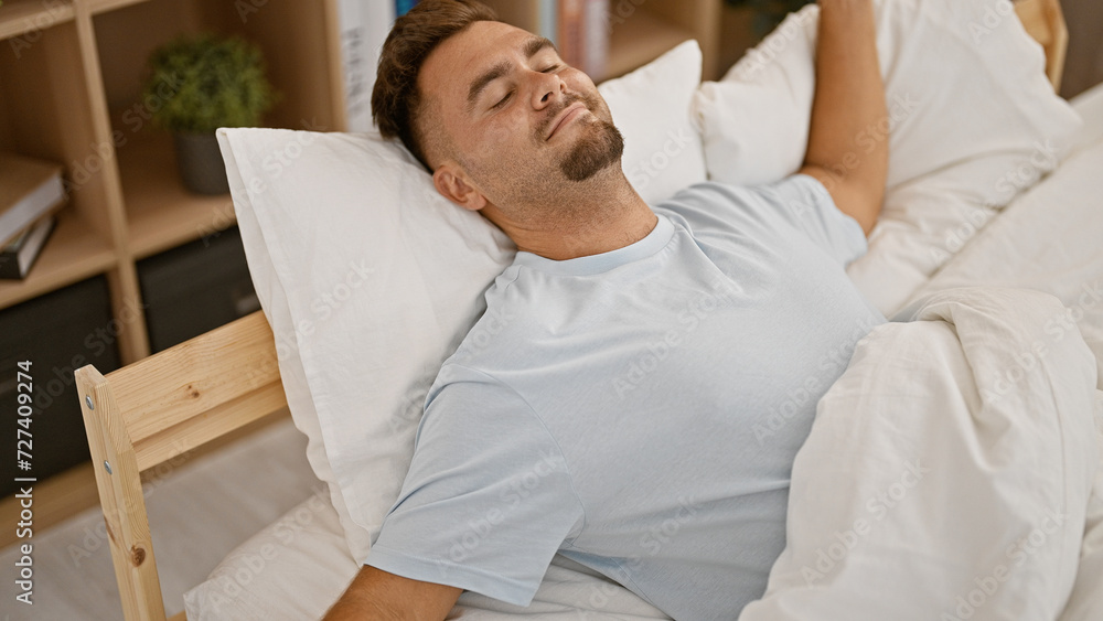 Obraz premium Handsome hispanic man resting in a bedroom with white bedding and a peaceful expression