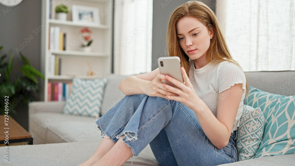 Young blonde woman using smartphone sitting on sofa at home Young blonde woman using smartphone sitting on sofa at home