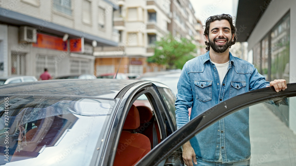 Young hispanic man smiling confident opening car door at street