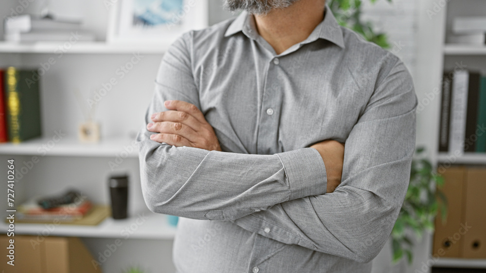 Confident senior hispanic man with a grey beard and hair, standing arms crossed in a modern office environment. Confident senior hispanic man with a grey beard and hair, standing arms crossed in a modern office environment.