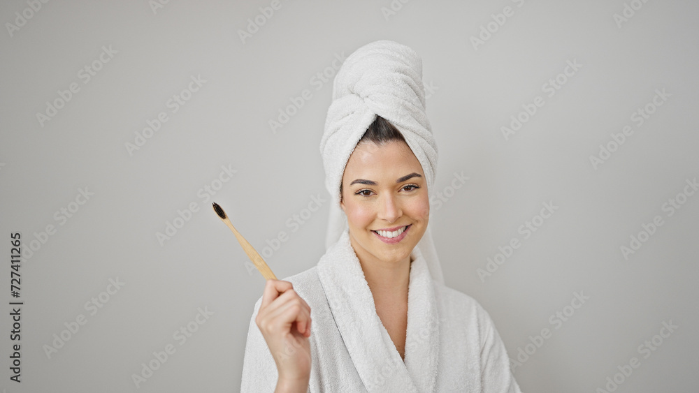 Young beautiful hispanic woman wearing bathrobe holding toothbrush over isolated white background Young beautiful hispanic woman wearing bathrobe holding toothbrush over isolated white background