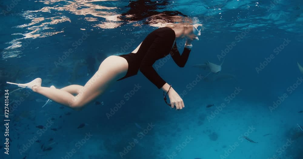 Woman freediver resting on the surface and dive to the deep in a tropical blue sea at Maldives Woman freediver resting on the surface and dive to the deep in a tropical blue sea at Maldives