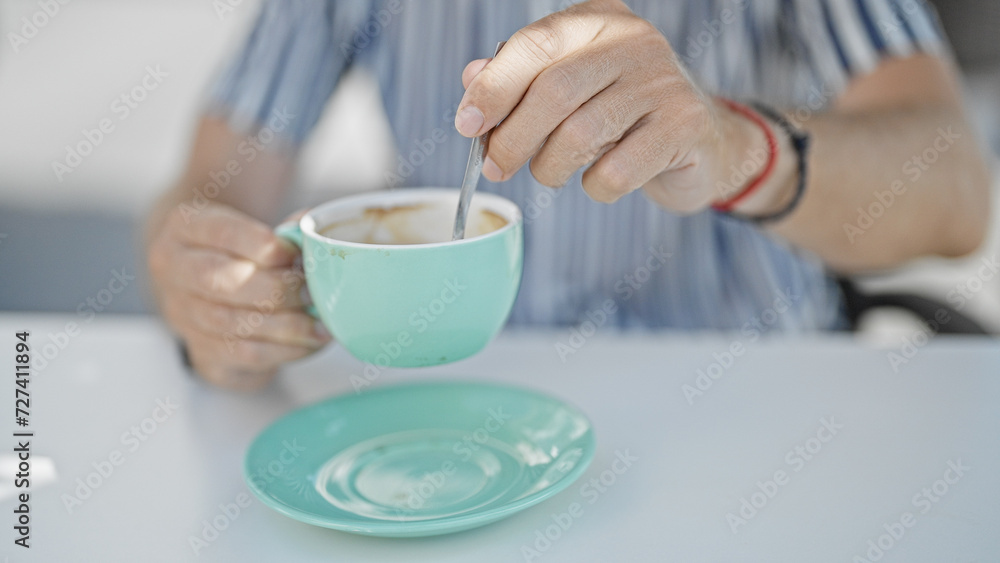 Close-up of a man stirring coffee in a turquoise cup at a modern cafe terrace. Close-up of a man stirring coffee in a turquoise cup at a modern cafe terrace.