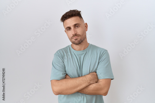 Hispanic man with beard standing over white background looking sleepy and tired, exhausted for fatigue and hangover, lazy eyes in the morning.