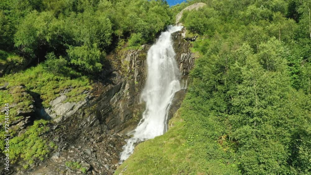 A large beautiful waterfall in the middle of the forest on a sunny evening. Juicy green colors. A large beautiful waterfall in the middle of the forest on a sunny evening. Juicy green colors.