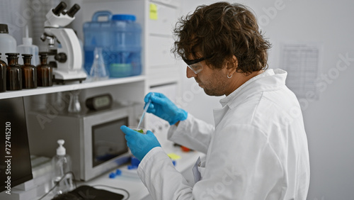 A man in a lab coat conducts an experiment in a science laboratory  handling test tubes and standing by equipment.