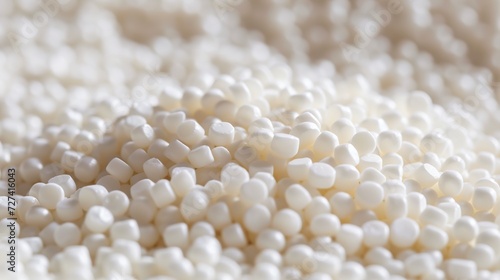 White plastic pellets of uniform texture, very small and shiny. Polymer matte white plastic granules of different shapes. Reuse of plastic waste in sustainable practices.