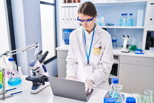 Young caucasian woman scientist using laptop at laboratory