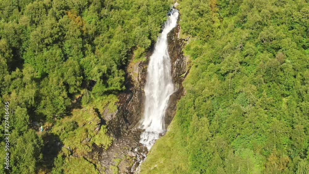 A large beautiful waterfall in the middle of the forest on a sunny evening. Juicy green colors. A large beautiful waterfall in the middle of the forest on a sunny evening. Juicy green colors.