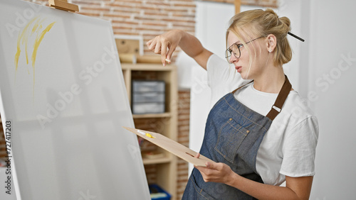 Young blonde woman artist looking draw thinking at art studio © Krakenimages.com