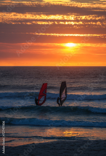 A couple windsurfing during a golden sunset at sunset beach, Cape Town, South Africa